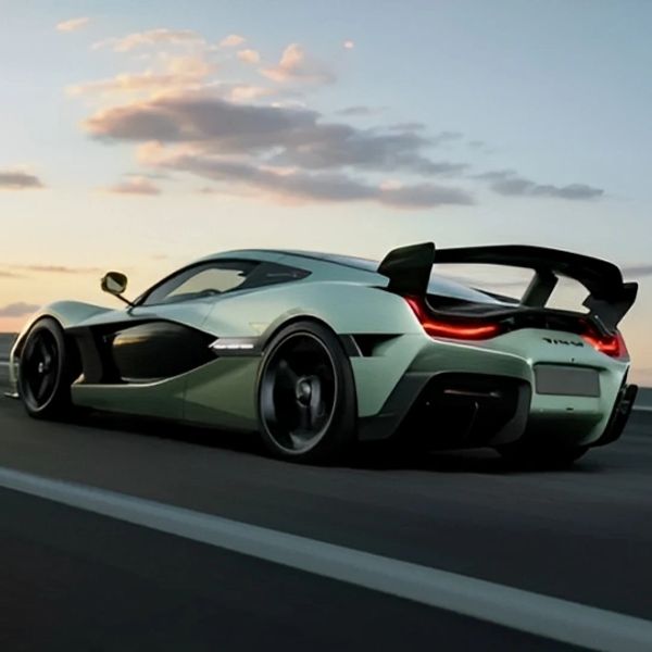 Sleek green hypercar with aerodynamic design speeding on an open road at sunset
