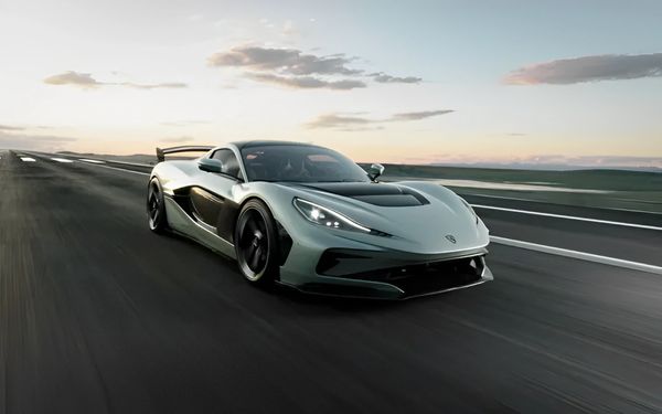 Sleek hypercar speeding down an open road at sunset, showcasing aerodynamic design and performance