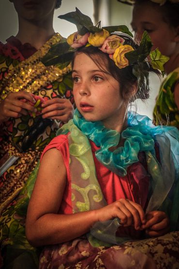 Young girl in floral headpiece and colorful scarf.
