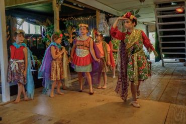 Children in colorful costumes rehearsing a play.
