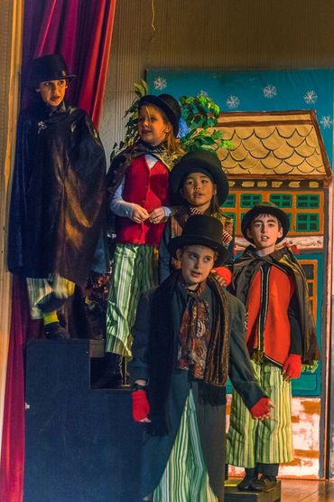 Children dressed in Victorian-era costumes standing on stage.