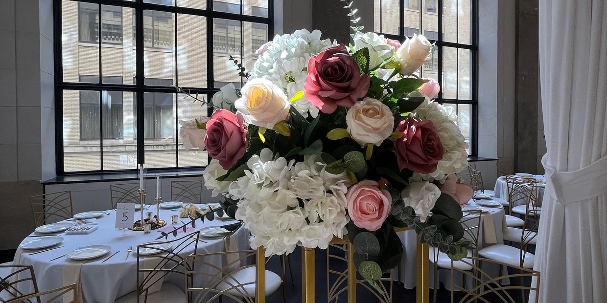 Elegant floral centerpiece with roses and hydrangeas at a banquet hall.