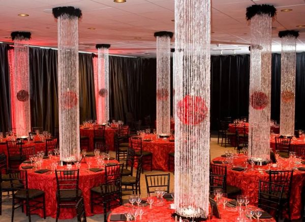 Elegant event space with red tablecloths and illuminated crystal columns.