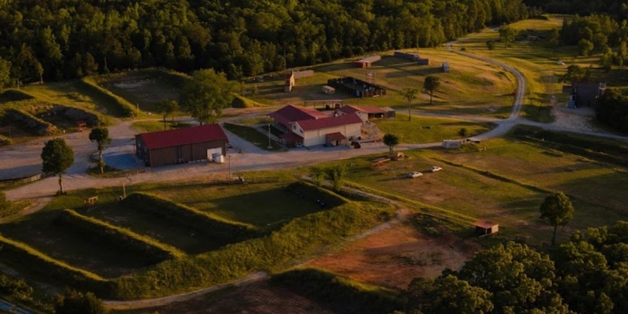 Aerial view of a rural property with buildings, dirt roads, and green fields.