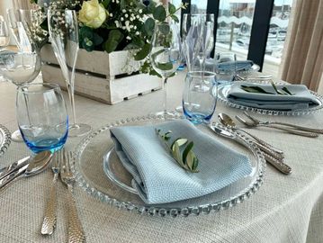Elegant table setting with blue napkins and clear glass plates.