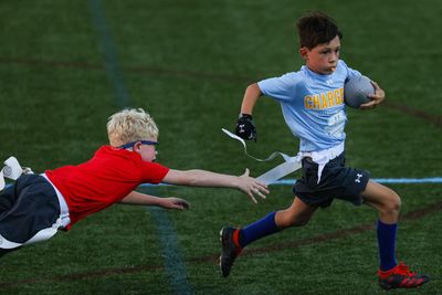 Two boys playing flag football, one trying to grab the other's flag.
