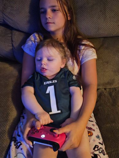 Young girl holding a baby playing with a game controller.