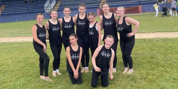 Group of young dancers posing outdoors in matching outfits.
