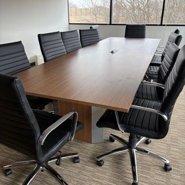 Empty modern conference room with black chairs around a wooden table.