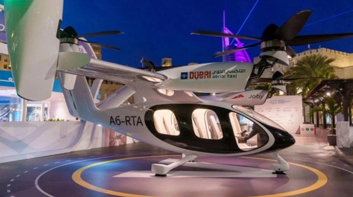 A sleek Dubai aerial taxi displayed at night with illuminated interior and rotor blades.
