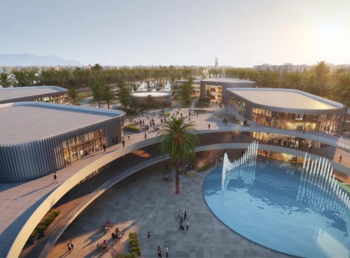 Modern shopping complex with curved architecture and a water fountain.