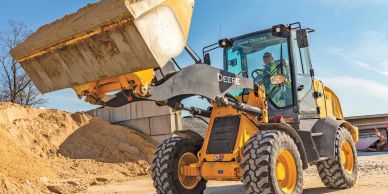 A yellow front loader moving sand at a construction site.