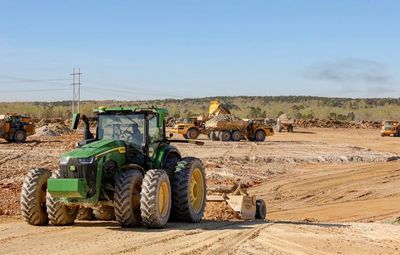 Green tractor working on a large construction site during the day.