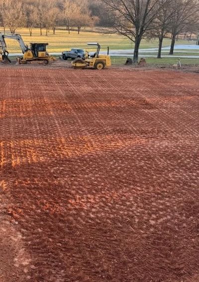 Construction site with leveled red dirt and machinery.