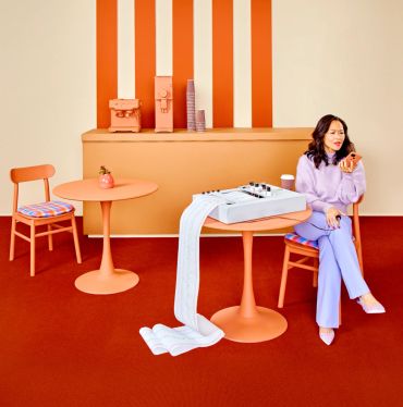 Woman in purple outfit sitting in a retro orange-themed room with a long receipt.