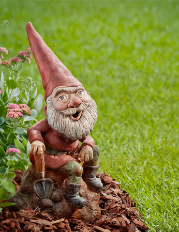 Cheerful garden gnome statue with a shovel and pointed hat.