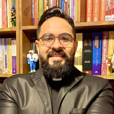 Colaborador Diego sorrindo tendo sua biblioteca como fundo.