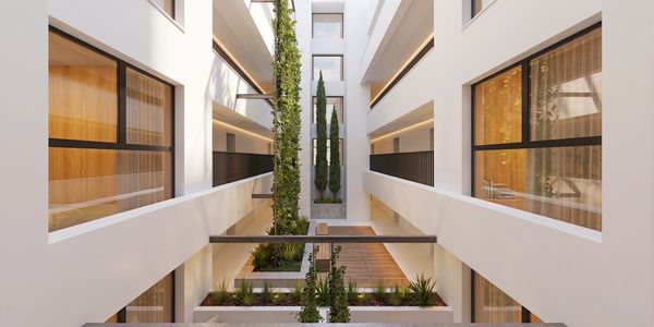 Modern apartment interior courtyard with greenery and large windows.