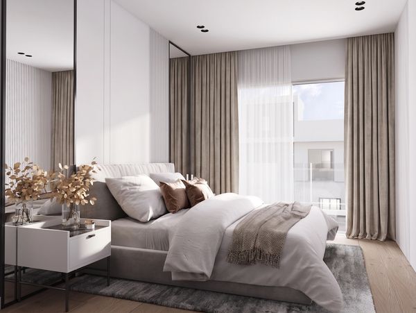 Modern bedroom with neutral tones and cozy bedding near a large window.