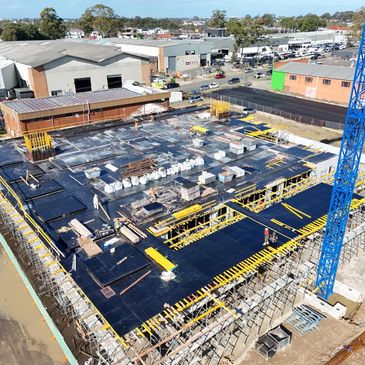 Construction site with concrete foundation and blue crane in an industrial area.