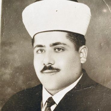 Vintage black-and-white portrait of a man wearing a traditional hat and suit.