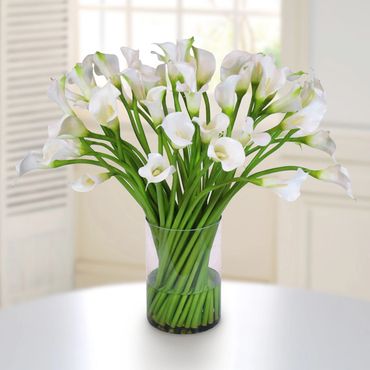 A bouquet of white calla lilies in a clear glass vase.