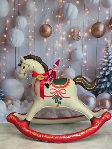 Elf doll on decorative rocking horse with festive background.