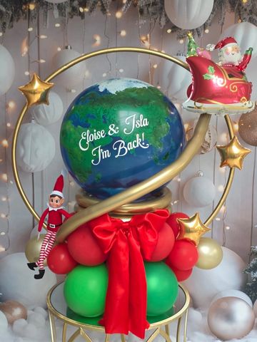 Festive globe balloon decoration with Santa and elf figures.