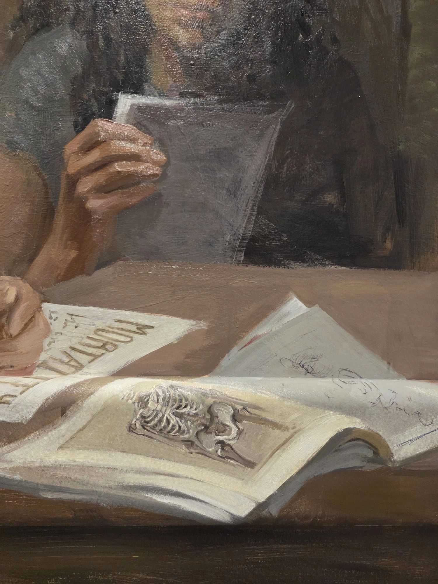 Person holding and reading various papers and a book with a skeleton illustration.
