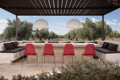 Outdoor seating area with red chairs and modern lighting under a pergola.
