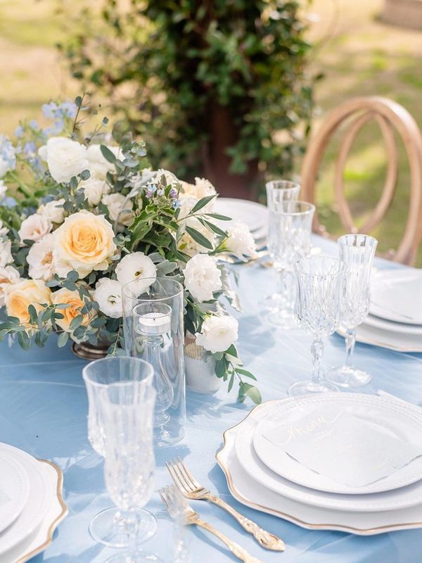 Elegant outdoor table setting with floral centerpiece and crystal glassware.