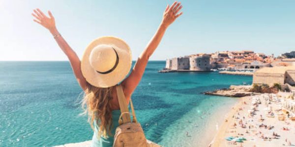 Woman with arms raised enjoying a scenic coastal view.