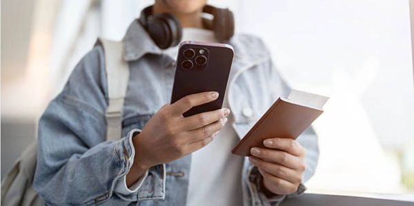 Person holding passport and smartphone, likely at an airport.