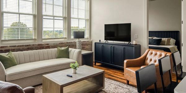 Modern living room with beige sofa and leather chairs.