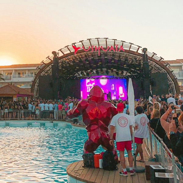 Crowd enjoying a sunset concert at Ushuaïa with a red gorilla statue by the pool.