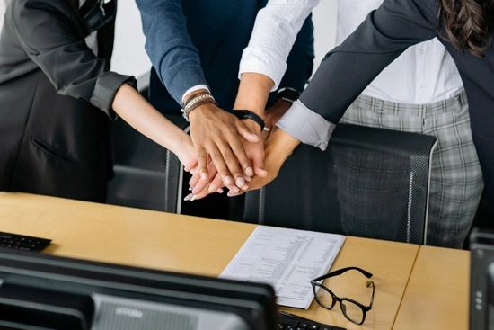 Colleagues placing their hands together in a teamwork gesture at the office.