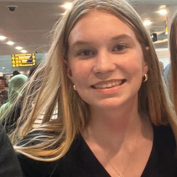 Smiling young woman with long blonde hair in a black top.