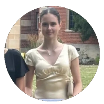 Young woman in a light gold dress standing outdoors with a serene expression.