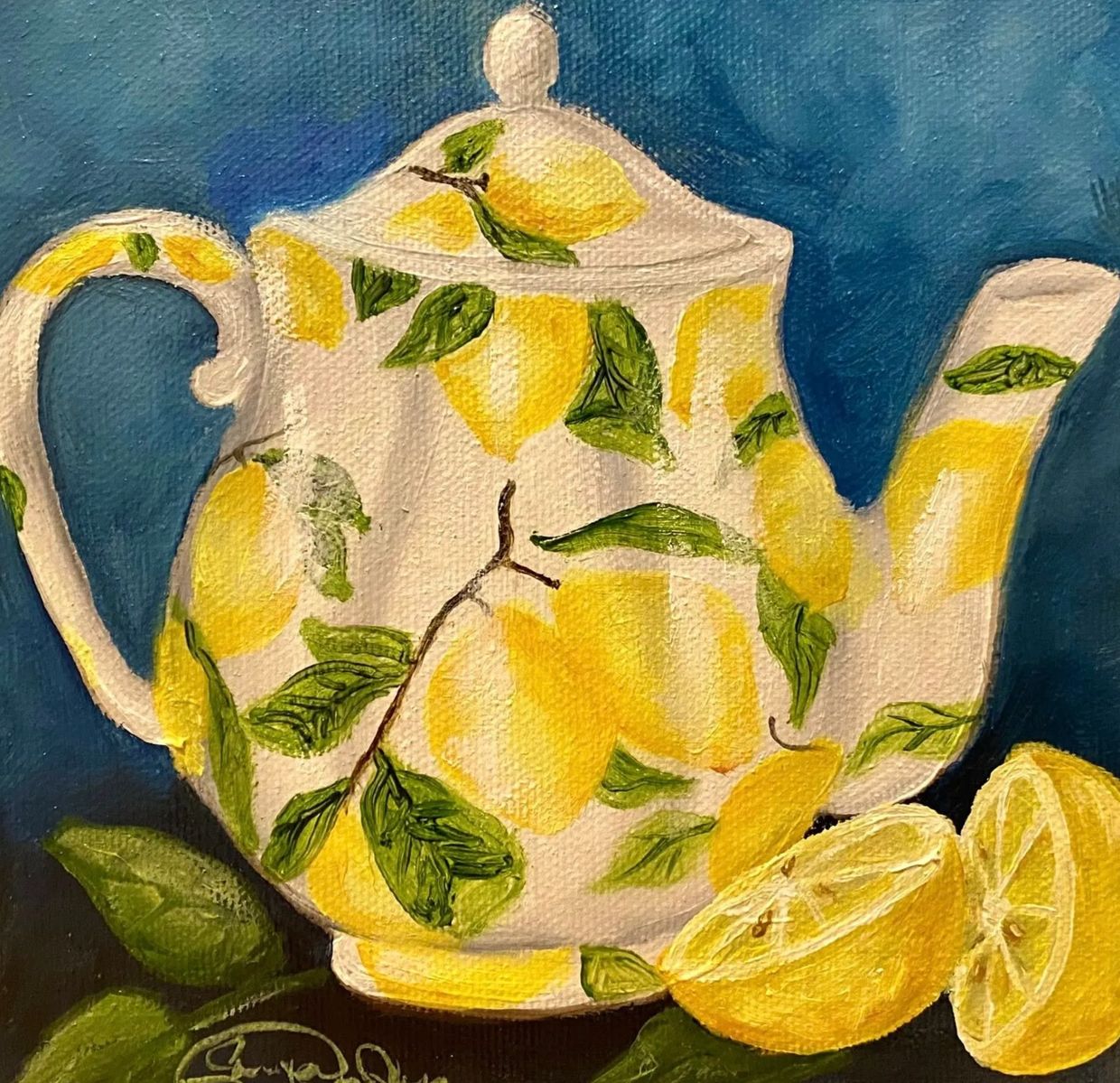 A teapot decorated with yellow lemons and green leaves, accompanied by two lemon halves.