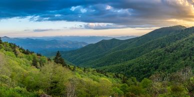 Lush green mountains under a dramatic sky during sunset.