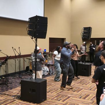 People performing on stage with microphones in a room.