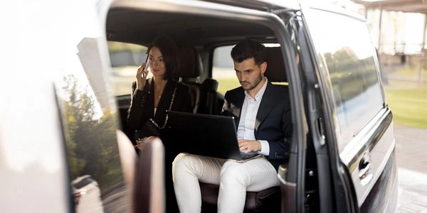 Businessman and businesswoman working inside a car.
