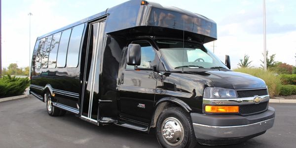 A sleek black limousine bus parked outdoors on a clear day.