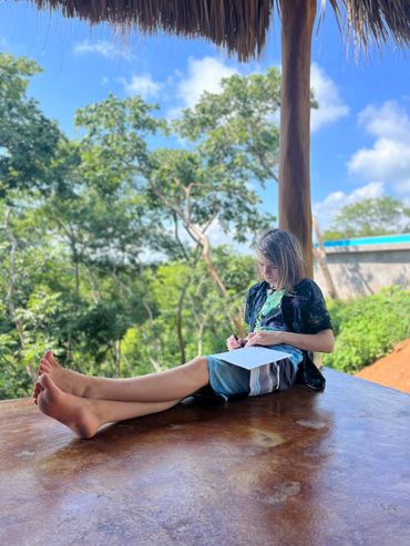 A boy working on his homeschool on an outside porch with a view.