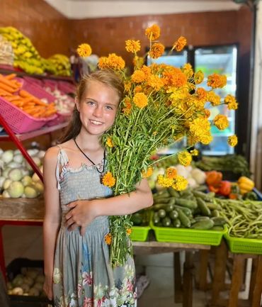 A girl at the mercado holding an armful of bright orange marigolds. 