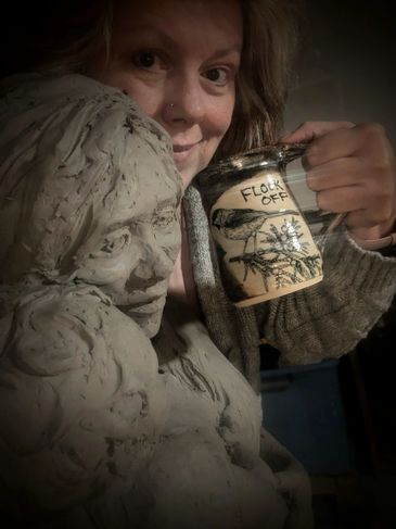 Person posing with a clay bust and a mug that says "Flock Off."