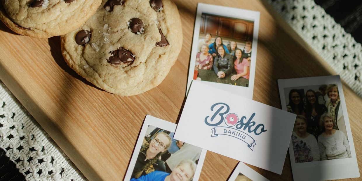 Chocolate chip cookies on a wooden board with Bosko Baking logo and family photos.
