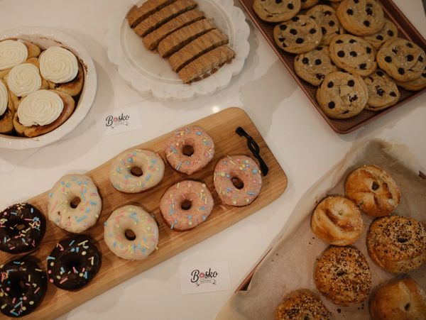 Assorted baked goods including donuts, cookies, and cinnamon rolls on a white table.