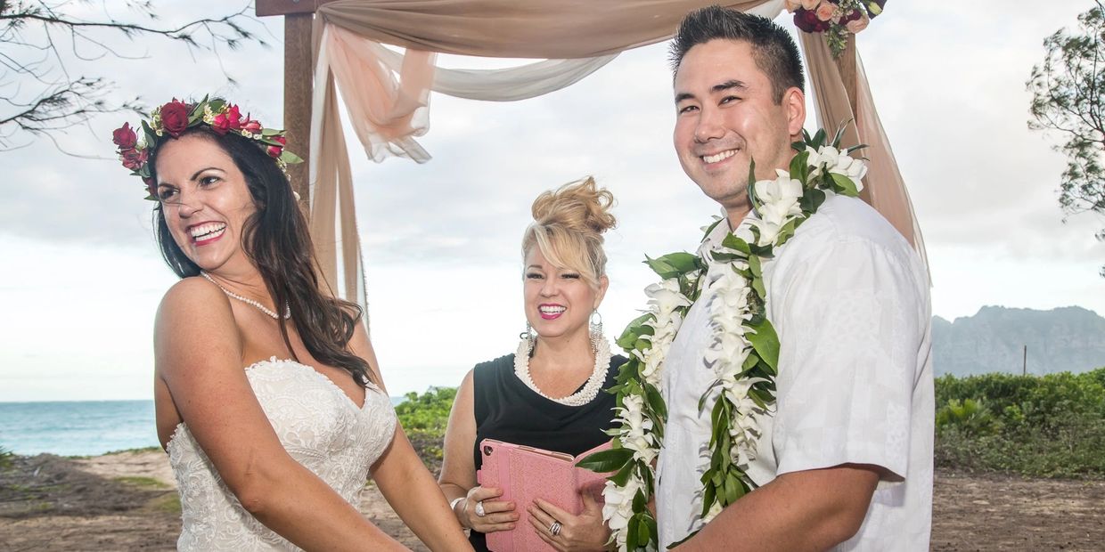 Joyful bride and groom holding hands during beach wedding ceremony.