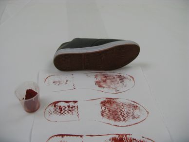 Shoe sole with red powder prints on white paper and a container of powder.